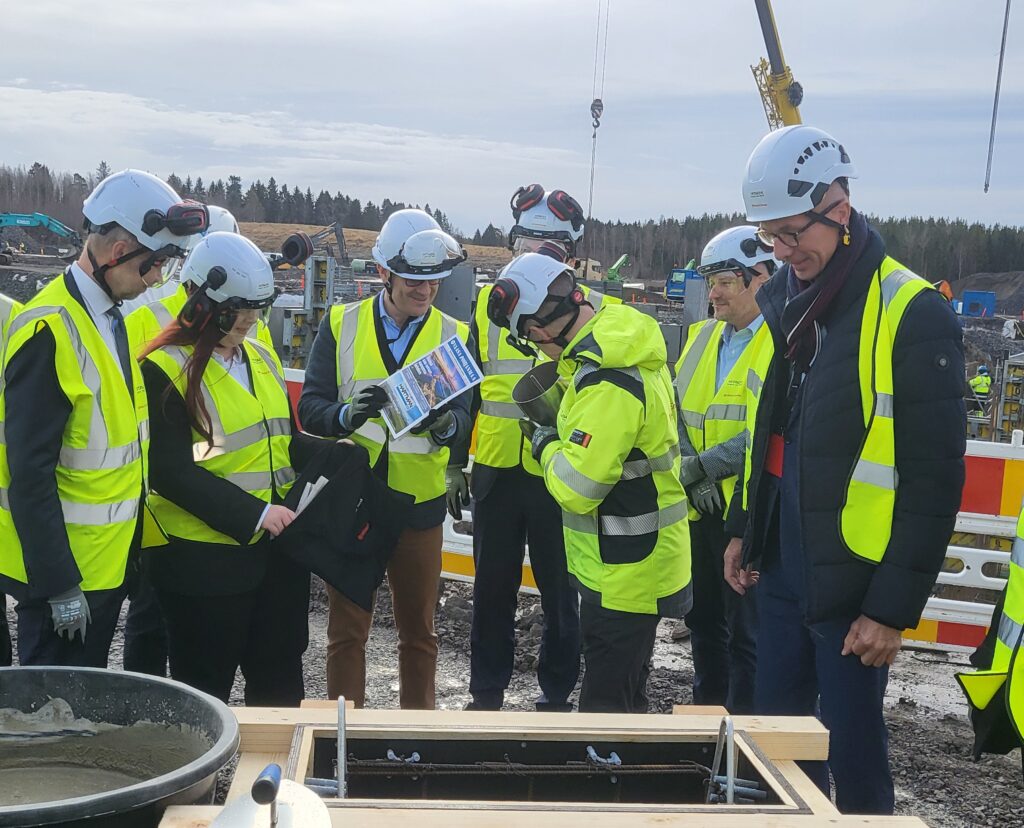 Hitachi Energys Bruno Melles placerar Vaasa Pohjanmaa-tidningen i grundstenen. Längst till vänster på bild Matti Vaattovaara.