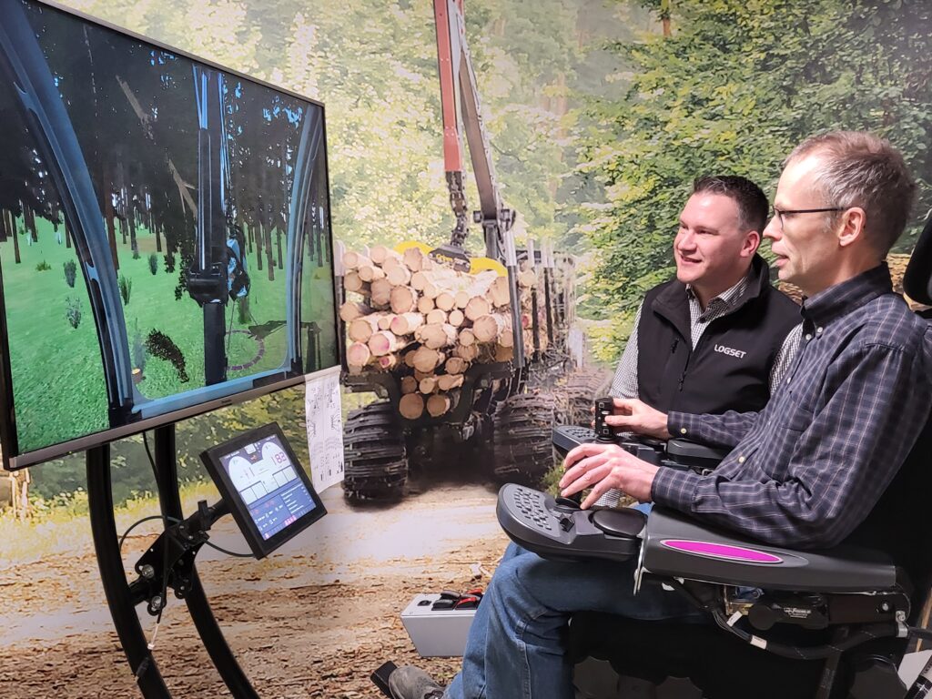 Automation Manager Tom Knipström näyttää, miten metsäkonesimulaattori toimii. Kuvassa myös toimitusjohtaja Ron Back.